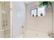 Bathroom featuring tiled shower, tub, and window bringing in natural light at 8531 Lake Dr, Snellville, GA 30039
