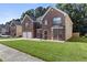 Two-story brick home featuring a well-manicured lawn, two-car garage and view of neighboring houses at 802 Cormac Dr, Riverdale, GA 30296