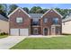 Charming two-story brick home featuring a well-manicured lawn, two-car garage, and lovely front yard landscaping at 802 Cormac Dr, Riverdale, GA 30296
