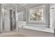 Bathroom featuring a soaking tub, decorative window, and glass-enclosed shower at 8935 Muirfield Ct, Duluth, GA 30097