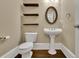 Charming powder room featuring a pedestal sink, oval mirror, and decorative wooden shelves at 8935 Muirfield Ct, Duluth, GA 30097