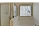 Bright bathroom featuring a tub with tiled surround, window with blinds and frameless glass enclosed shower at 2421 Fall Creek Lndg, Loganville, GA 30052