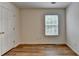 Bright bedroom featuring wood-look flooring, a window with blinds, and a white door leading to the hallway at 2421 Fall Creek Lndg, Loganville, GA 30052