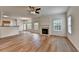 Open-concept living room with wood floors, fireplace, ceiling fan, and easy access to dining and kitchen at 2421 Fall Creek Lndg, Loganville, GA 30052