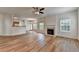 Open-concept living room with wood floors, fireplace, ceiling fan, and easy access to dining and kitchen at 2421 Fall Creek Lndg, Loganville, GA 30052