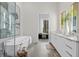 Bright bathroom featuring a soaking tub, double vanity, and an open doorway to an adjacent bedroom with city views at 40 12Th St # 1004, Atlanta, GA 30309