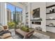 Living room with city view featuring a leather sofa, chair, modern fireplace, and decor on shelves at 40 12Th St # 1004, Atlanta, GA 30309