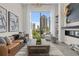 Living room with city view featuring a leather sofa, chair, modern fireplace, and decor on shelves at 40 12Th St # 1004, Atlanta, GA 30309