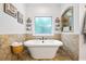 Bright bathroom features a stand-alone tub with travertine tile and a decorative mirror at 1005 Renfroe Lake Dr, Auburn, GA 30011