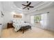 Bedroom with a tray ceiling features a large window, neutral carpet, and a bench at the foot of the bed at 1005 Renfroe Lake Dr, Auburn, GA 30011