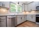Well-lit kitchen with stainless steel dishwasher, granite counters, light grey cabinets and modern fixtures at 5525 Belle Meade Dr, Villa Rica, GA 30180