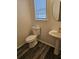 Cozy powder room with wood-look floors, pedestal sink and natural light from window at 4845 Weathervane Dr, Alpharetta, GA 30022
