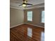 Bright bedroom with hardwood floors, tray ceiling, and natural light from two windows at 4845 Weathervane Dr, Alpharetta, GA 30022