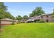 Large, well-maintained backyard featuring a lush green lawn, mature trees, and outbuildings at 1535 Pathfinder Sw Way, Lilburn, GA 30047