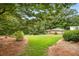 Lush backyard featuring a large lawn, mature trees, and a charming outbuilding at 1535 Pathfinder Sw Way, Lilburn, GA 30047