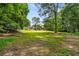 Spacious backyard with a well-maintained lawn, mature trees, and a view of the outbuilding at 1535 Pathfinder Sw Way, Lilburn, GA 30047