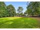 Expansive backyard with lush green lawn, mature trees, and an outbuilding with a garage at 1535 Pathfinder Sw Way, Lilburn, GA 30047