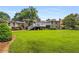 Expansive backyard with a well-manicured lawn, mature trees, and a two-story brick home with a deck at 1535 Pathfinder Sw Way, Lilburn, GA 30047