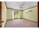 Bright bedroom featuring neutral carpet, ceiling fan, and large window overlooking mature landscaping at 1535 Pathfinder Sw Way, Lilburn, GA 30047