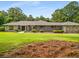 Beautifully landscaped front exterior of a brick and stone home with an expansive lawn and mature trees at 1535 Pathfinder Sw Way, Lilburn, GA 30047