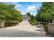 Long concrete driveway leading to a two-car garage, surrounded by mature trees and landscaped bushes at 3906 Laurens Ln, Snellville, GA 30039