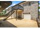 Exterior view of a two-car garage and an elevated deck with black railing and stairs at 3906 Laurens Ln, Snellville, GA 30039