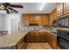 Charming kitchen with granite counters, wood cabinets, tiled floors and backsplash, and sleek black appliances at 3906 Laurens Ln, Snellville, GA 30039