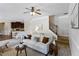 Sunlit living room features a ceiling fan, white sofa, and seamless flow into the kitchen area at 4249 Caveat Ct, Fairburn, GA 30213