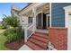 Inviting front porch with brick stairs, blue siding, white columns, and landscaped garden at 326 Still Pine Bnd, Smyrna, GA 30082