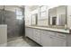 Bright bathroom featuring a double vanity, granite countertop, framed mirrors, and a glass-enclosed shower with gray tiling at 4452 Thach Ave, Sugar Hill, GA 30518