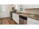 Updated kitchen features stainless steel appliances, granite counters, white cabinets, and wood-look flooring at 2191 Greystone Way, Decatur, GA 30032