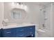 Bright bathroom with a blue vanity, white countertop, decorative mirror, and a shower-tub combination with white tile at 104 Trinity Hollow Dr, Canton, GA 30115
