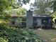 Rear exterior featuring a chimney, lots of windows, and mature landscaping at 512 Rockborough Ter, Stone Mountain, GA 30083