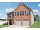View of the brick exterior elevation of the home with attached two-car garage at 1363 Midnight Ride Ct, Hampton, GA 30228