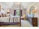 Bright bedroom features a four-poster bed, tray ceiling and sitting area near a window at 3820 Ridge Point Dr, Suwanee, GA 30024