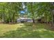 Beautiful home exterior with wooded views, a deck, and a charming outbuilding at 675 Mayes, Powder Springs, GA 30127
