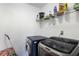 Bright laundry room with black washer and dryer with wire rack shelving above machines at 949 Tumlin Trce, Lawrenceville, GA 30045