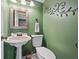 Stylish powder room with green walls, pedestal sink, and decorative mirror at 1809 Claron Ave, Conley, GA 30288