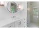 Bright bathroom features a circular mirror, vanity with storage, and glass-enclosed shower with tiled walls at 819 Loridans Dr, Atlanta, GA 30342