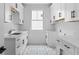 Well-lit laundry room featuring white cabinetry, quartz countertops, a stainless steel sink, and patterned tile flooring at 819 Loridans Dr, Atlanta, GA 30342
