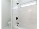 Modern bathroom featuring a bathtub and shower with sleek, white tile and black hardware accents at 3284 Hall Rd, Dacula, GA 30019