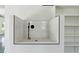 A modern white tiled shower stall with black hardware and pebble floor inside the home at 3284 Hall Rd, Dacula, GA 30019