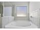 Bathroom featuring a soaking bathtub with tiled walls, glass shower doors and a window at 2260 Cedar Place Ct, Snellville, GA 30078