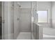 The shower with glass doors and tiled walls, as well as a small window and a bathtub nearby at 2260 Cedar Place Ct, Snellville, GA 30078
