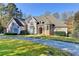 Stately two-story home with a circular driveway and lush landscaping on a sunny day at 3871 River Mansion Dr, Peachtree Corners, GA 30096