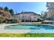 Backyard view of the inviting pool with seating, complemented by the home's architecture and surrounding landscaping at 3871 River Mansion Dr, Peachtree Corners, GA 30096