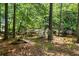 Wooded backyard with a creek, an outdoor seating area, and a sign pointing to the lake at 2945 Cardinal Lake Cir, Duluth, GA 30096