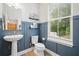 Stylish powder room with blue paneled walls, pedestal sink, and a window providing natural light at 1150 Buice Lake Pkwy, Acworth, GA 30102
