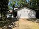 Charming single-story home featuring white siding, black trim, and a spacious driveway, surrounded by mature trees at 1771 Kristi Dr, Lawrenceville, GA 30043