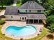 Aerial view of a backyard featuring a kidney-shaped pool, stone patio, covered porch, and lush greenery at 3559 Turtle Cove Se Ct, Marietta, GA 30067